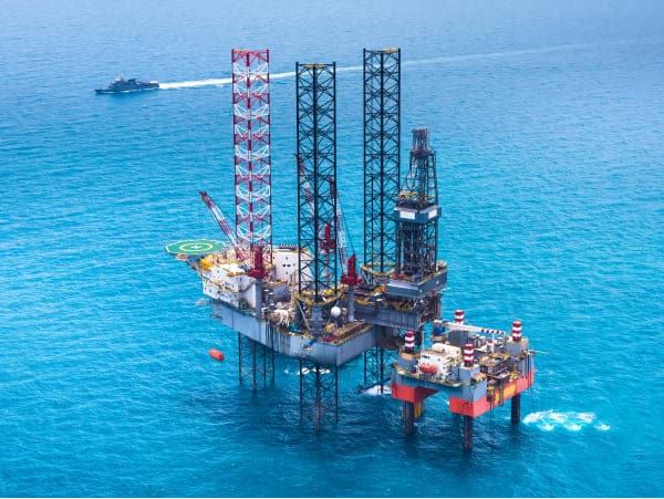 offshore oil rig from distance on water level with ship background